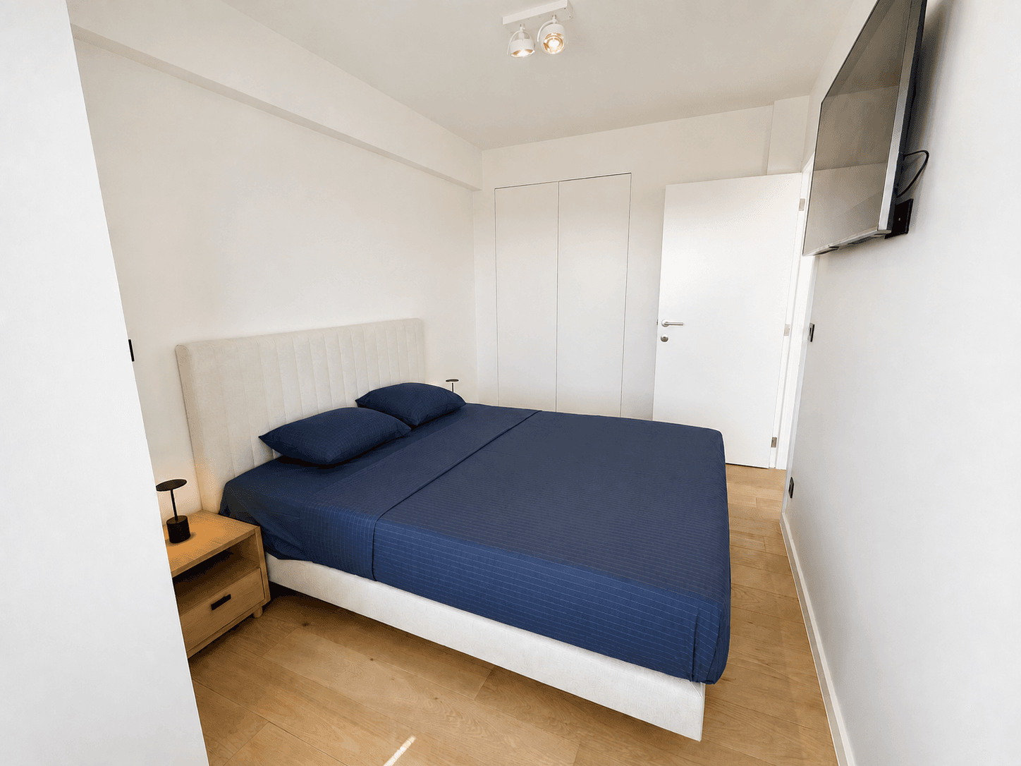 Tweepersoonskamer met blauw bedlinnen en zachte kusttinten