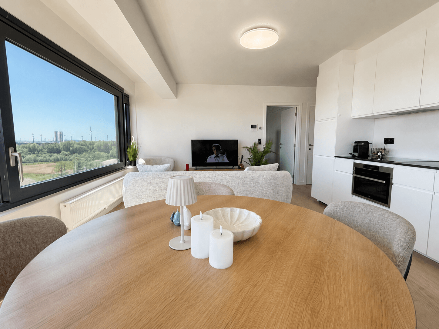 Ronde eettafel naast de open keuken en grote ramen